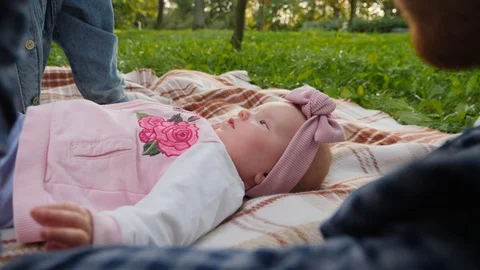 Young parents playing with his infant baby child daughter lying together on a Video stock 117697953