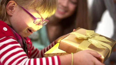 Young parents presenting a gift box to their daughter under a christmas tree Stock Footage