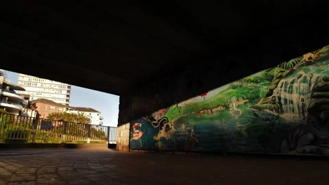 Young parents push pram past clean sea mural in Sydney slow motion dolly 4K Video stock 246093420