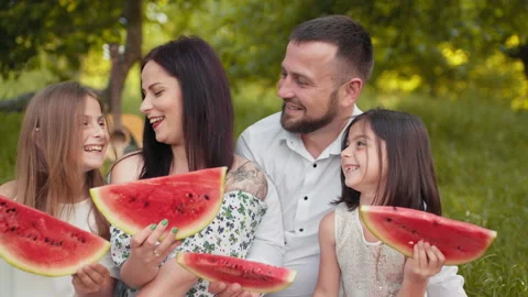 Young parents with two pretty daughters spending free time at green garden and Stock Footage 157325916