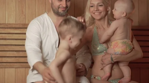 Young parents with two sons in the thermal zone bask in the sauna Stock Footage