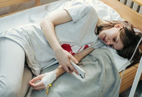 Young Patient Using Smartphone in Bed Stock Photos