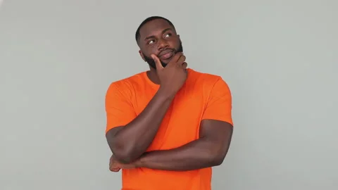 Young pensive dreamful thoughtful bearded african american guy 20s in orange Stock Footage 148317654