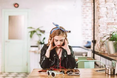 Young pensive lady in leather jacket sitting and thoughtfully lookig at many Stock Photos
