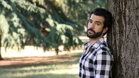Young pensive man at park thinking leaning against a tree Stock Footage 136548507