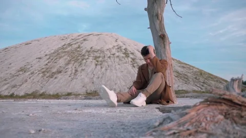 Young pensive man sitting under a tree  lost in his thoughts Stock Footage 138260183
