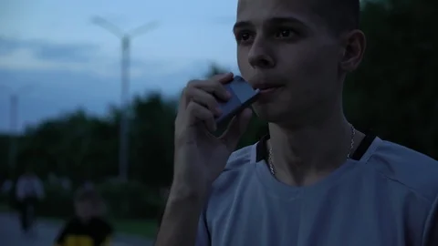 Young pensive man smoking electronic tobacco heating system on the street in the Video stock 108657645