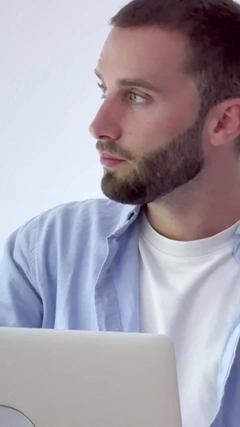 Young pensive professional man working on a laptop, thoughtfully looking away Video stock 346822702