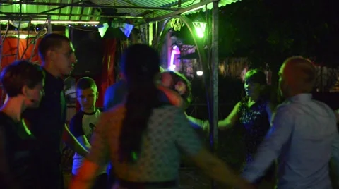Young people are dancing around couple at dark place with color lights. Stock Footage 65451462