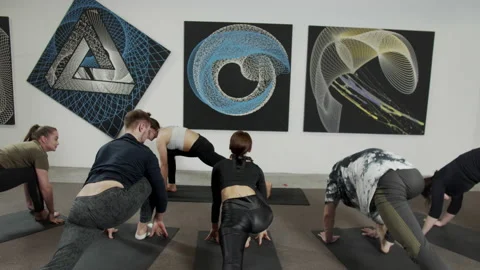Young people bend as low as possible during a yoga class in a small studio with Stock Footage 156480485