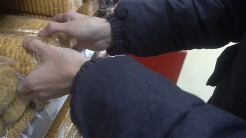 Young people bere in the store from a shelf a packet of biscuits and treats and Stock-Footage 82733713