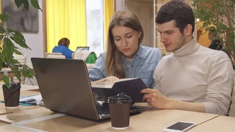 Young people browse some book at the working hub Stock Footage 76324345