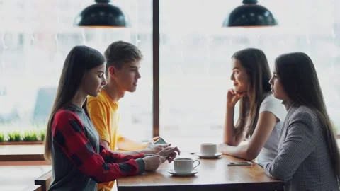 Young people chatting at a table in a cafe. Stock Footage 143964053