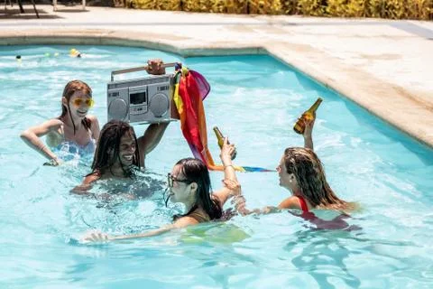 Young people of different ethnicities drinking party beer in a swimming pool Stock Photos