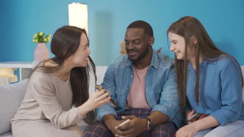 Young people of different races looking at the phone at home and laughing. Stock Footage 228801762