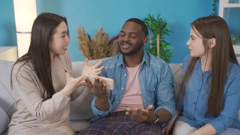 Young people of different races, looking at the phone, chatting and laughing. Stock Footage 228801797