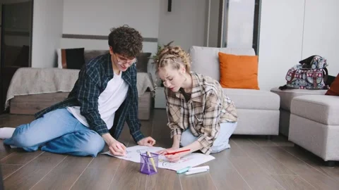 Young people drawing together on the floor in a modern living room with soft 库存影片 346185779