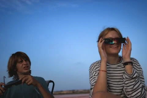 Young people enjoying a solar eclipse, wearing protective glasses while obs.. Stock Photos