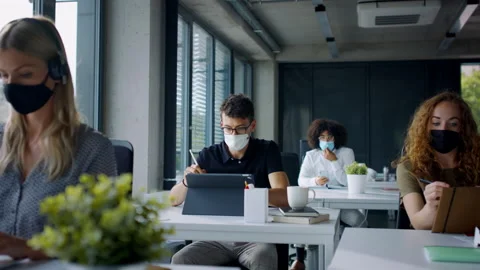 Young people with face masks back at work or school in office after lockdown. Stock Footage 133356231
