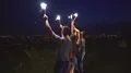 The young people with firework sticks dancing on the city background. night time 4k or 4k+ Resolution