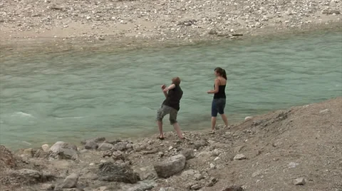 Young people have fun throwing stones on water Vídeos de archivo 32376573
