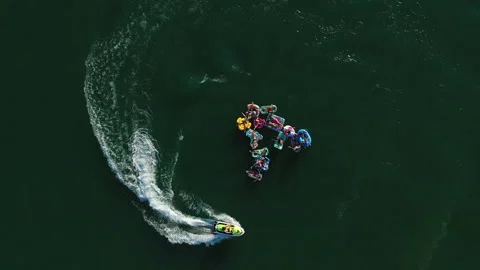 Young people having fun on water floats at a lake on vacation with a jet ski. Stock Footage 204743358