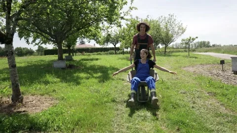 Young people having fun in yard, playing with wheelbarrow Video stock 130369800