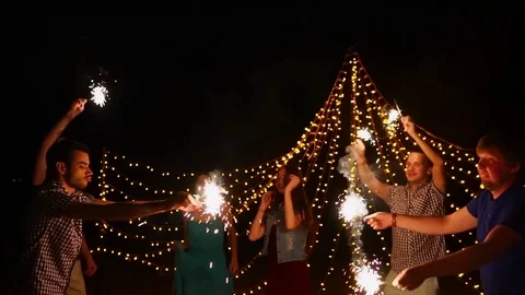 Young people having night beach party and dancing with sparklers Stock Footage