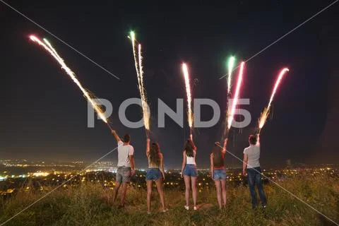 The young people hold firework sticks. evening night time Stock Photos