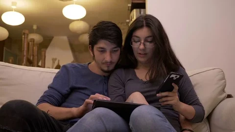 Young people at home man using tablet pc and woman smart phone shopping and p Video stock 83083230