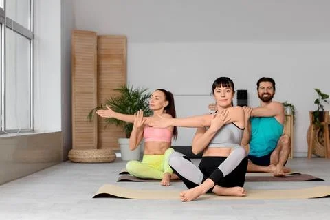 Young people with instructor practicing yoga in gym Stock Photos