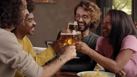Young people laughing and drinking in a pub. Group of friends celebrating a Stock Footage 245765006