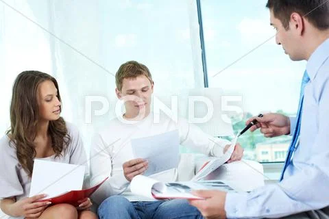 Young people looking through documents to find the best insurance program Stock Photos