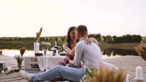 Young people in love hug while sitting on a decorated wooden deck. 库存影片 140875809