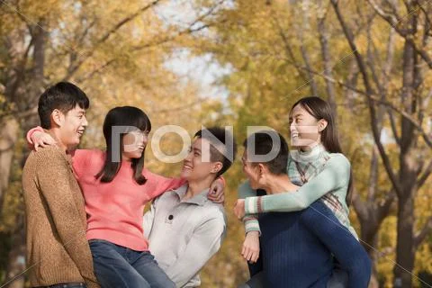 Young people playing piggyback in park Stock Photos