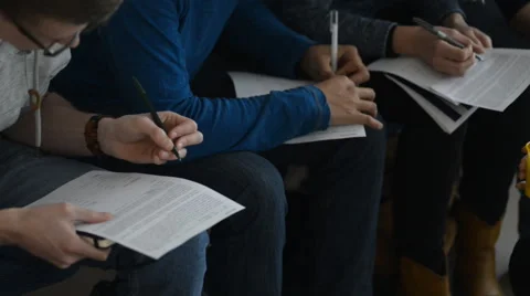 Young people in a row make records, laying sheets of paper on their lap Stock Footage 61513419