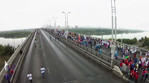 Young people run a marathon on a large bridge across the river Stock Footage 65233765