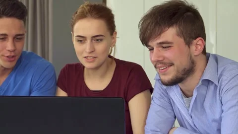 Young people share laughter at a table with a laptop Stock Footage 311981663