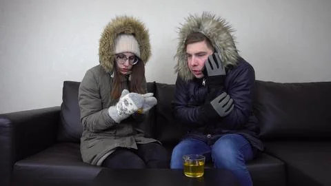 Young people sit at home on the devan in the triggers because of the cold in the Stock Photos