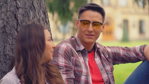 Young people sitting leaned on tree in campus. Video stock 126286581