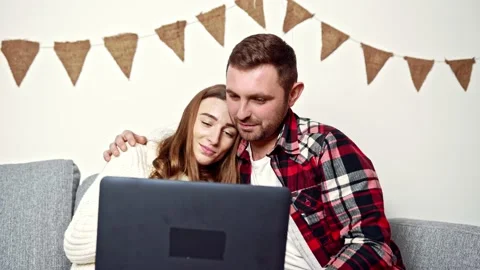 Young people sitting under a warm blanket and looking at something in a laptop Stock-Footage 150402865