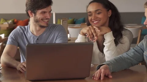 Young people smiling about what they see on laptop at the cafe Stock Footage 74307053