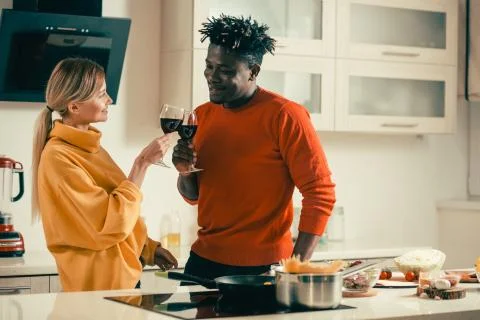 Young people smiling while clanging glasses with red wine Stock Photos