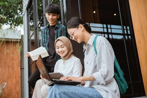 Young people using laptop while sitting near glass window Stock Photos