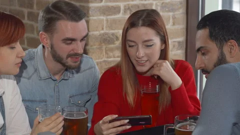 Young people using smart phone while drinking beer together at the pub Stock Footage 148763573