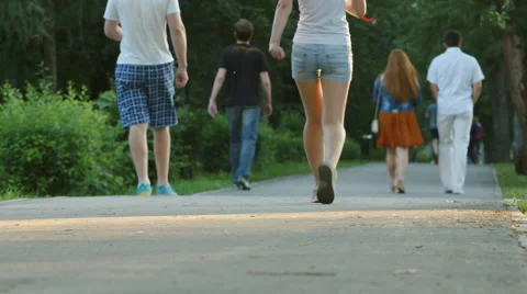 Young people walk in a park - feet level Stock Footage