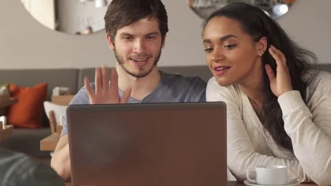 Young people wave their hands to the laptop screen at the cafe Stock Footage 74306595
