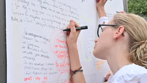 Young people writing their prayers onto a sheet during Mladifest in Medjugorje Stock Footage 228445274