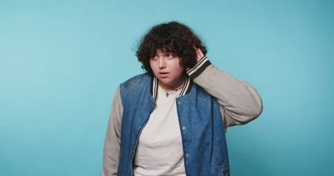 Young person in a blue background making funny faces at the camera while to.. Vídeos de archivo 328247230
