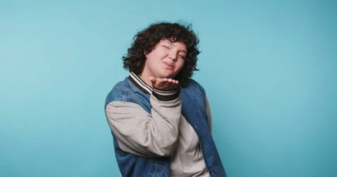 Young person expressing emotions while standing against a blue backdrop in .. Stock Footage 313951573